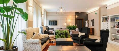 A modern living room with a sofa, armchairs, a coffee table, and a large potted plant.