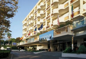 Un hotel con varios balcones, una entrada destacada y banderas de diferentes países.