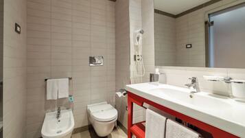 A modern bathroom with a bidet, toilet, and a large mirror above a sink.