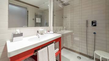 A modern bathroom with a large mirror, two sinks, a shower, and a toilet.
