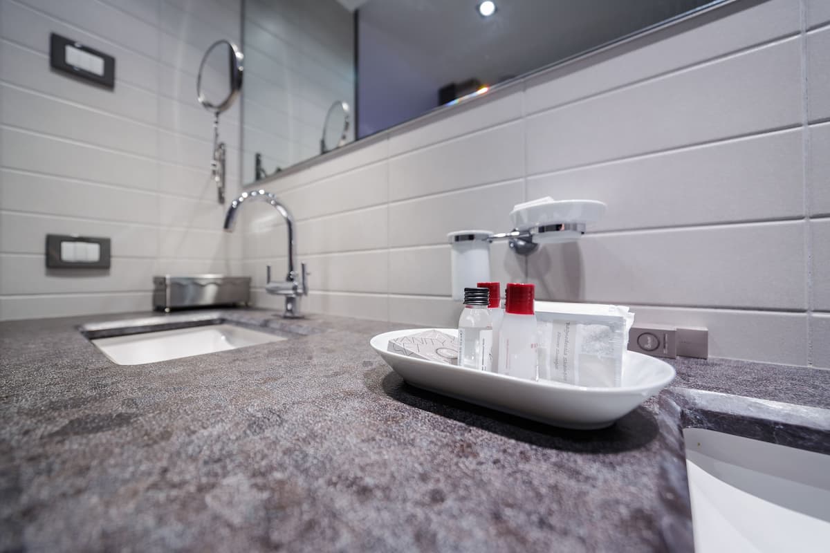 A bathroom with a granite countertop, a sink, and a mirror. There are toiletries on the counter.