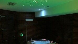 Een kamer met een massagetafel, een jacuzzi en een plafond met hangende lampen.
