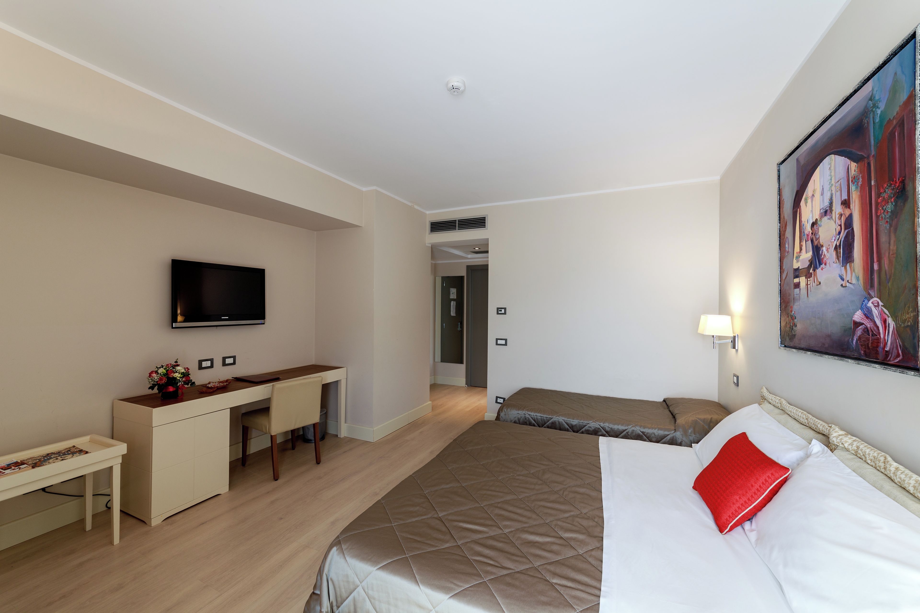 Une chambre d’hôtel avec un lit, un bureau, une télévision et un tableau au mur.