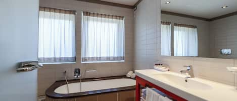 A modern bathroom with a bathtub, a sink, and a large mirror.