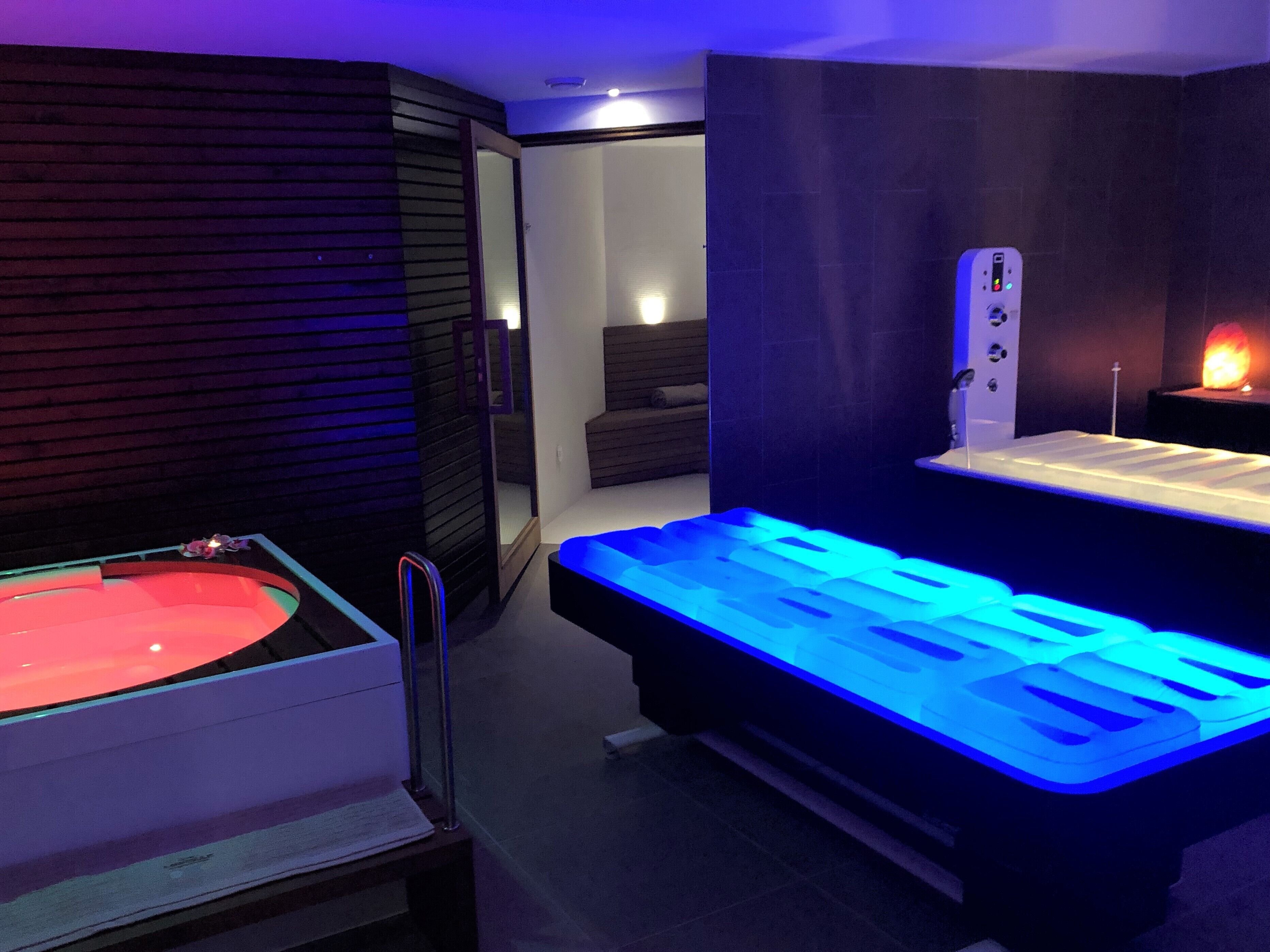 Una habitació d'spa moderna amb un bany de pedra climatitzat, una taula de massatge i una sauna.