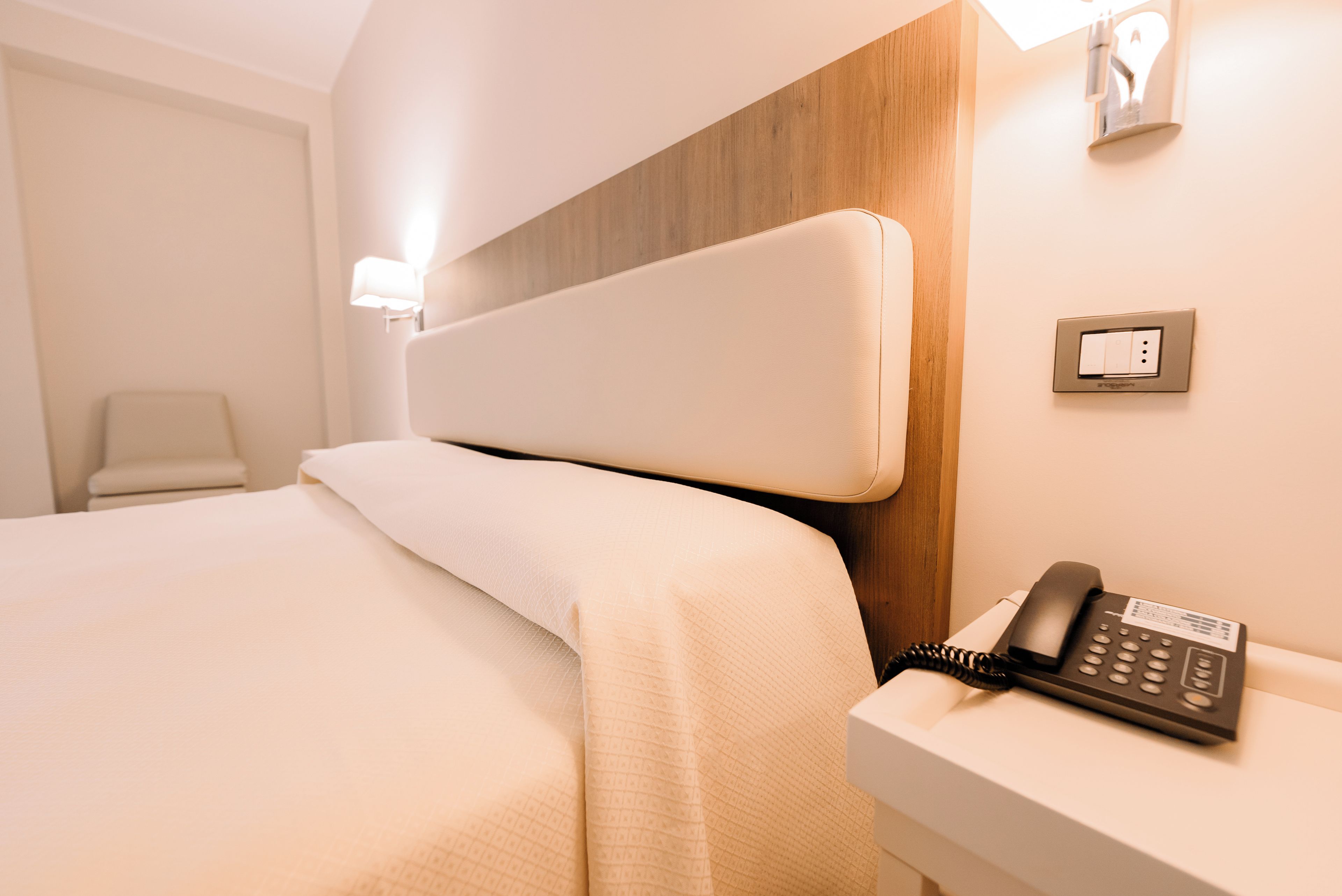 Una habitación de hotel con cama, mesita de noche, lámpara y teléfono.