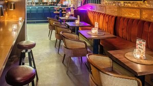 Una zona de bar con taburetes, mesas y un letrero de neón.