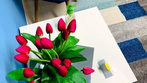 A white table with a bouquet of red tulips and a small bottle of hand sanitizer. - Bed and Breakfast Triscele (Sciacca)