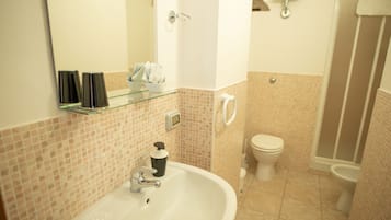 A bathroom with a white sink, a glass shelf, a toilet, and a shower area.