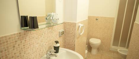 A bathroom with a white sink, a glass shelf, a toilet, and a shower area.