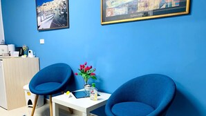 A room with two blue chairs, a small white table, a vase with red flowers, and two framed pictures on the wall. - Bed and Breakfast Triscele (Sciacca)