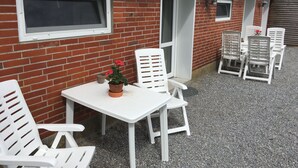 A brick building with a white door, a window, and a table with chairs. - Bed and Breakfast Tistrup (Tistrup)