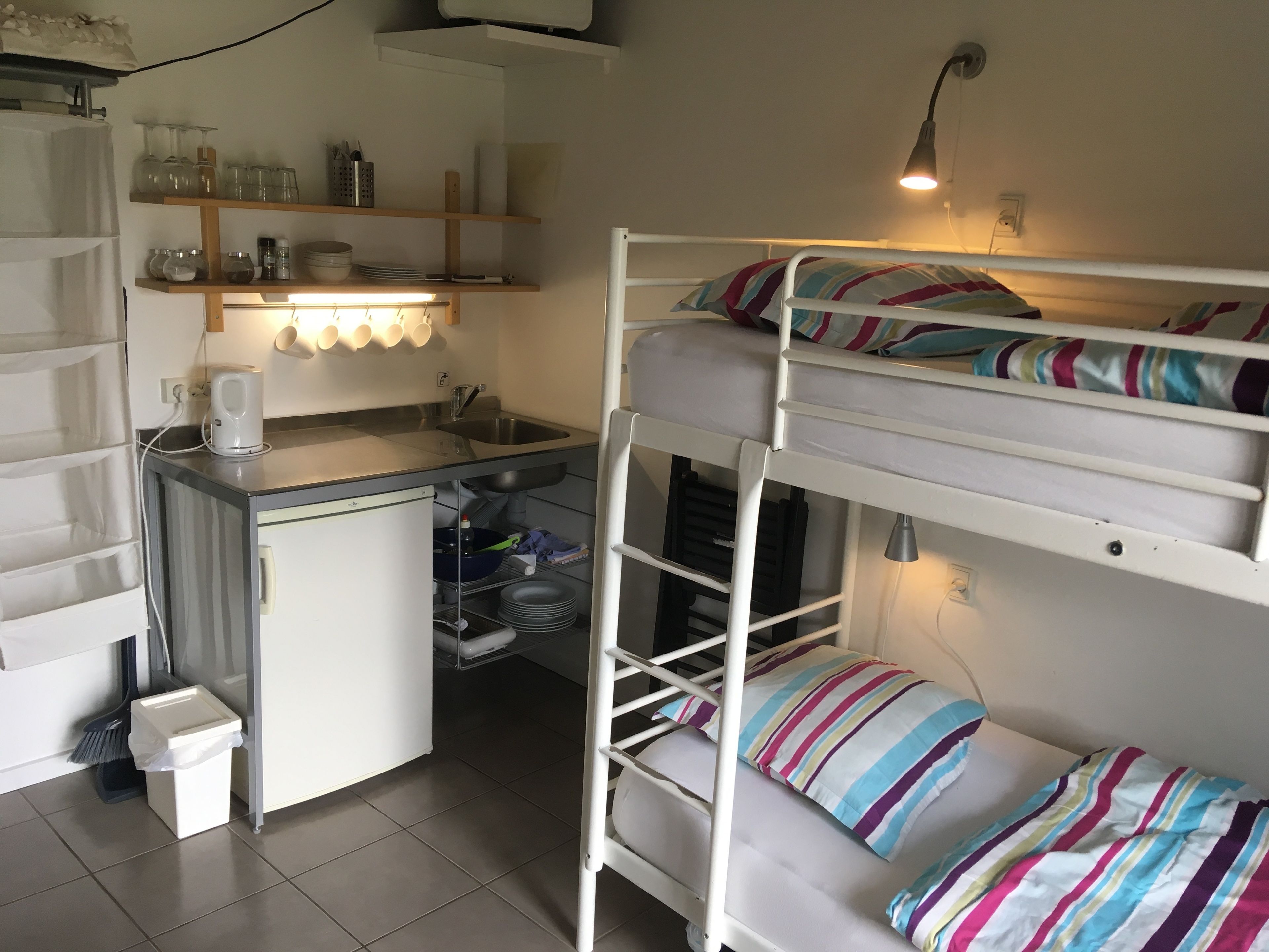 Habitación pequeña con literas, kitchenette y baño reducido.