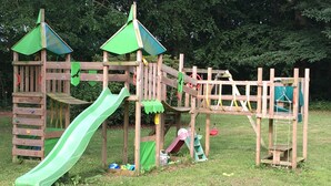 A wooden playground structure with a slide, climbing net, and various play elements. - Bed and Breakfast Tistrup (Tistrup)