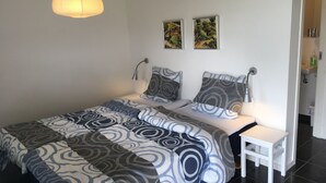 Une chambre à coucher moderne avec un lit, des tables de chevet, une lampe suspendue et deux tableaux accrochés au mur.