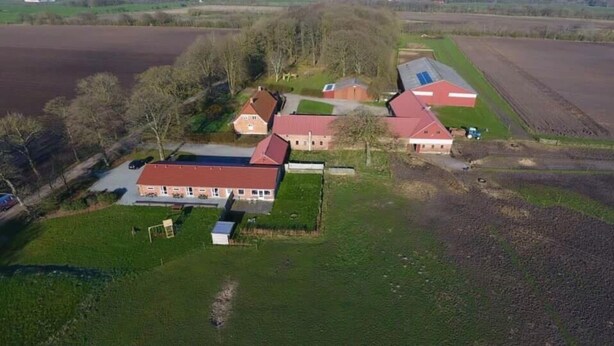 An aerial view of a farm with several buildings, including a main house with a red roof, barns, and fields. - Bed and Breakfast Tistrup (Tistrup)