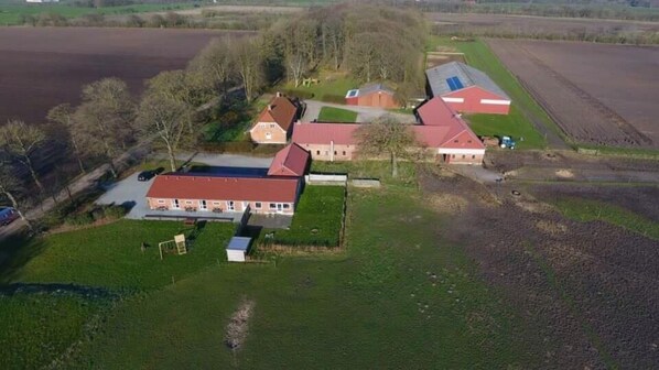 An aerial view of a farm with several buildings, including a main house with a red roof, barns, and fields. - Bed and Breakfast Tistrup (Tistrup)