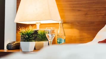 Una mesita de noche con una lámpara, una botella de agua, un vaso y una pequeña planta.