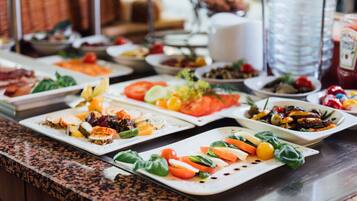 Un bufé con diversos platos, incluyendo ensaladas, quesos y carnes.