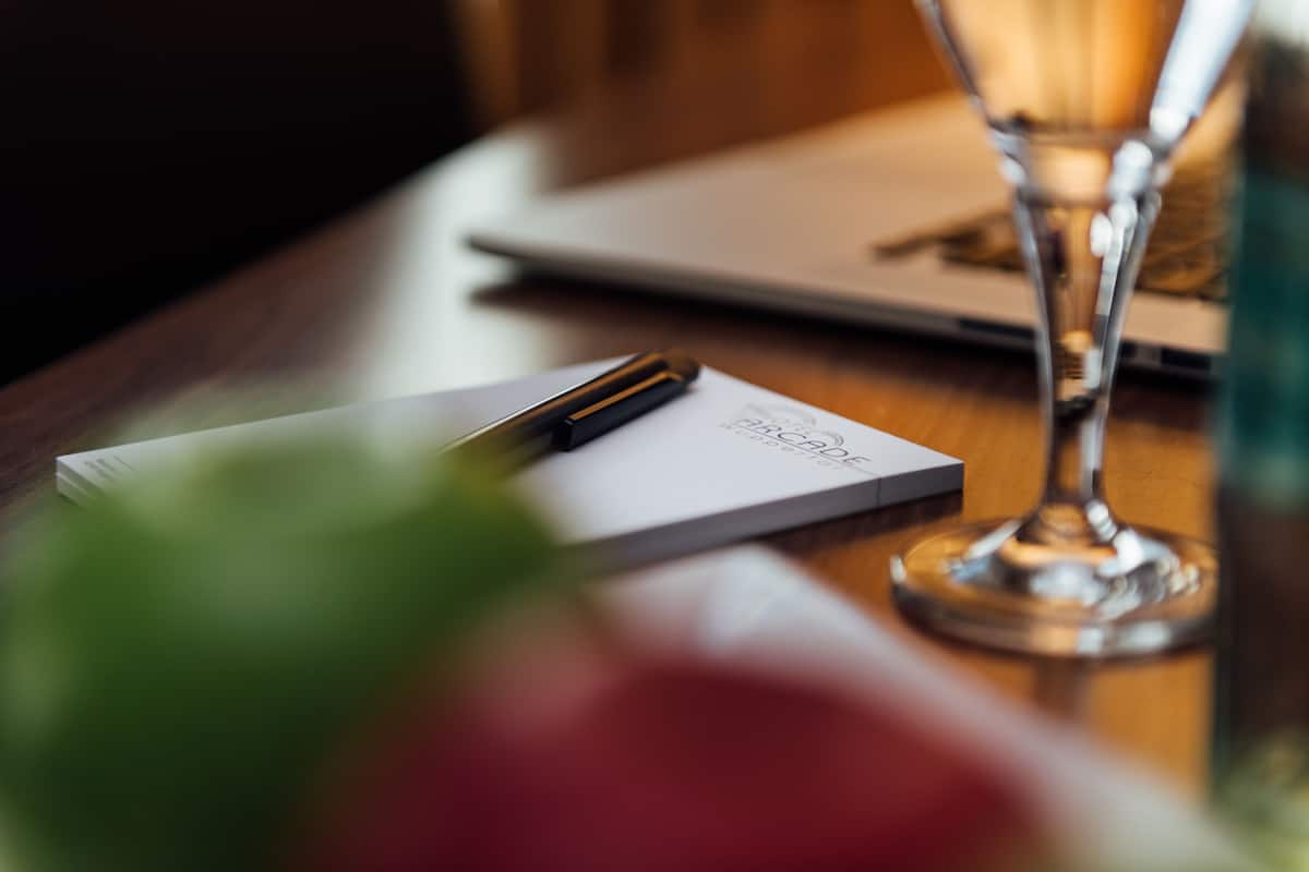 A wooden table with a laptop, a pen, and a glass of water.