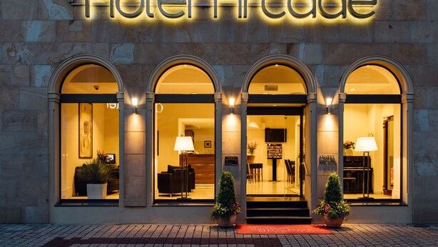 Hotel Arcade med buede vinduer, et receptionsområde og potteplanter.