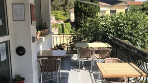 Un balcón con mobiliario exterior, una planta en maceta y vistas del vecindario circundante.