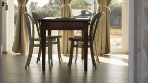 Een eetruimte met een houten tafel en stoelen, beige gordijnen en hangende吊り明かり.