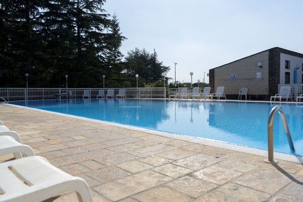 En säsongsöppen utomhuspool, parasoller och solstolar