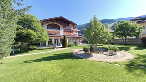 Un hôtel doté d’une pelouse bien entretenue, d’un jardin circulaire et d’un paysage montagneux en toile de fond.