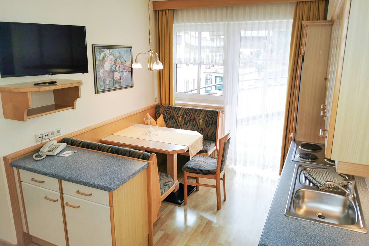 Une petite cuisine équipée comprenant un évier, une cuisinière et un coin repas avec une table et des chaises.