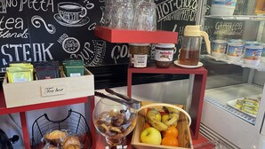 A tea box, a basket of bread, and a fruit basket on a counter with a chalkboard background. - Au Chapon Fin (Poitiers)