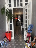 A hallway with a potted plant, a red pot, and a display rack with books and magazines.