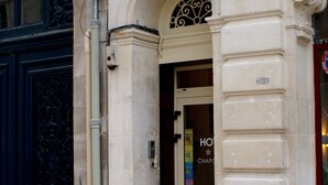A hotel entrance with a sign reading "Hotel Au Chapon Fin," a large arched doorway, and a decorative metal grille above the door. - Au Chapon Fin (Poitiers)
