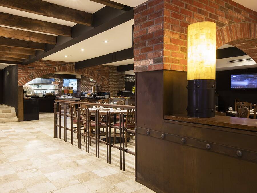 A bar area with a brick wall, wooden ceiling beams, and a television screen.