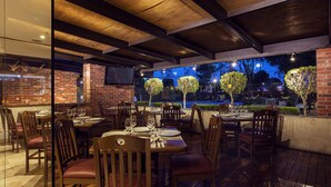 An outdoor dining area with brick walls, wooden tables, and chairs. - Krystal Urban Aeropuerto Cd de Mexico (Mexico City)