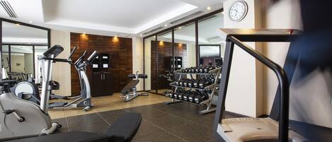 Ein Fitnessraum mit Trainingsgeräten, einer Bank und einem Laufband.