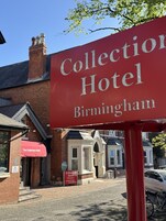 Une enseigne rouge pour l’hôtel Collection Hotel Birmingham, avec un bâtiment en briques en arrière-plan.