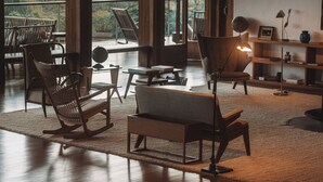Un salón amplio con un gran ventanal, muebles de madera y una estantería.