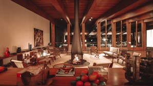 Una sala de estar acogedora con chimenea, muebles de madera y un ventanal grande.