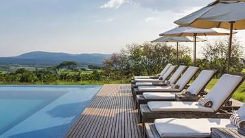 Una piscina techada, una piscina al aire libre, sombrillas