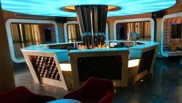 A bar area with a central column, two bar counters, and red chairs.