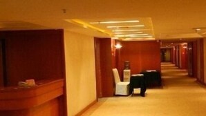 A hotel hallway with a reception desk, a seating area, and a carpeted floor.