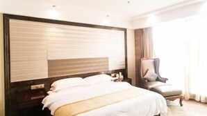 A hotel room with a large bed, a chair, and a wooden headboard.