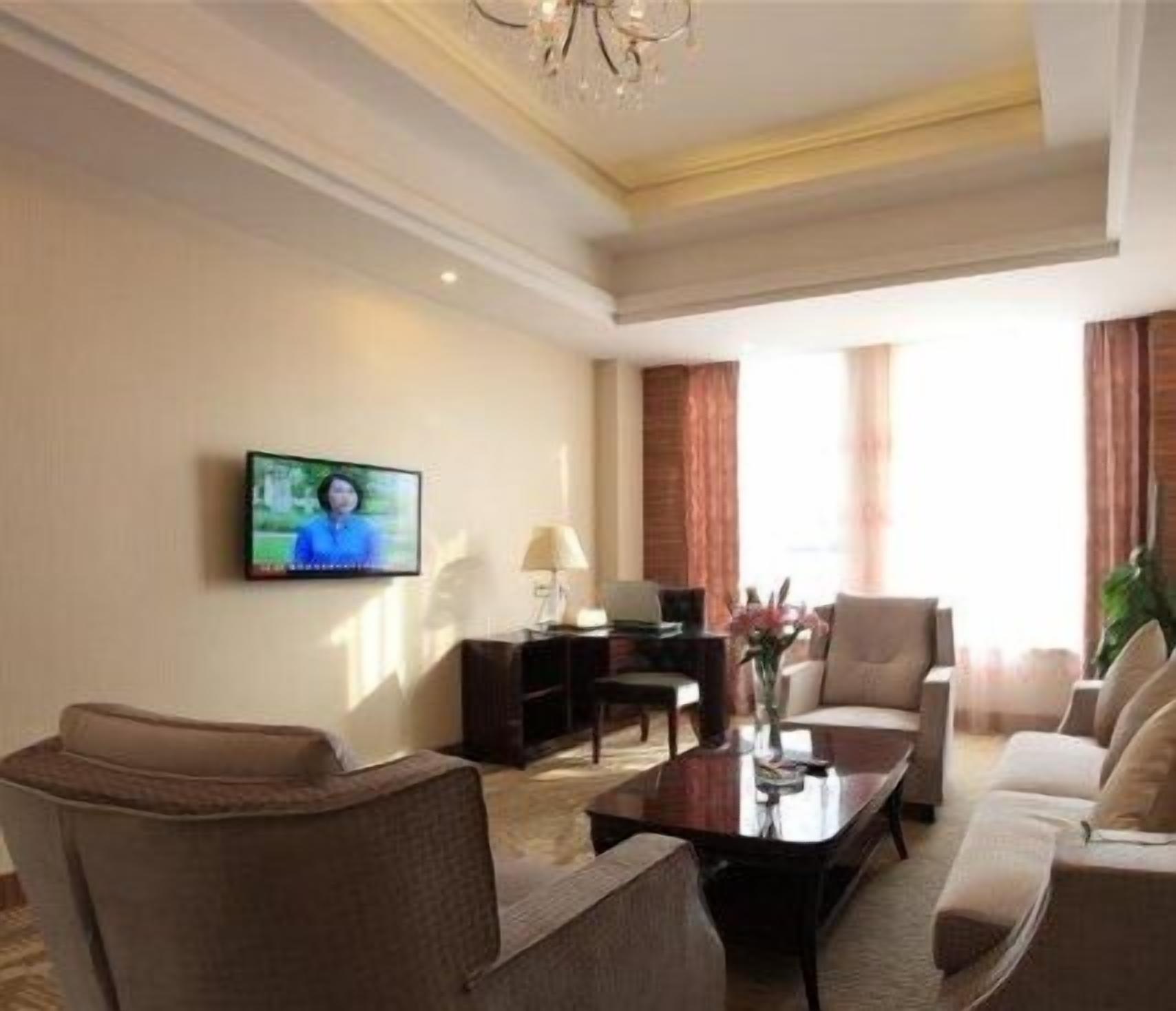 A living room with a television, sofa, armchairs, a coffee table, and a lamp.