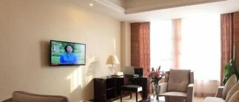 A living room with a television, sofa, armchairs, a coffee table, and a lamp.