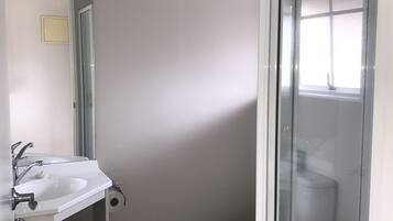 A bathroom with a white sink, mirror, and toilet.