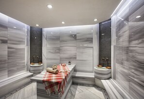 A modern bathroom with a marble floor and walls, a bench with a red and white checkered towel, and two sinks with decorative bowls. - Dedeman Zonguldak (Zonguldak)