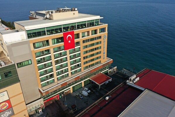 A multi-story hotel with a flag on the roof, a view of the sea, and a Burger King sign nearby. - Dedeman Zonguldak (Zonguldak)