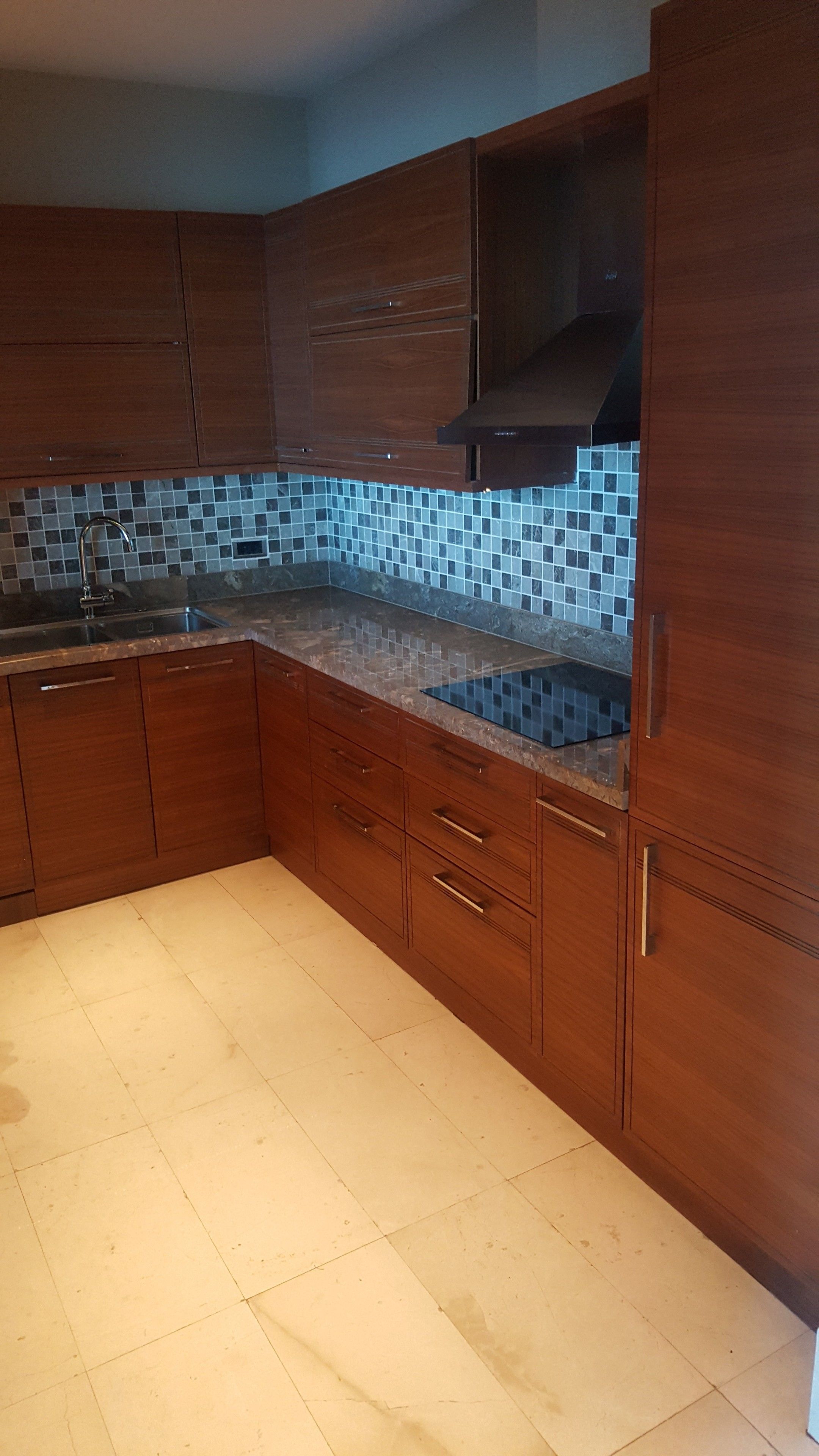 A kitchen with wooden cabinets, a tiled backsplash, and a tiled floor.