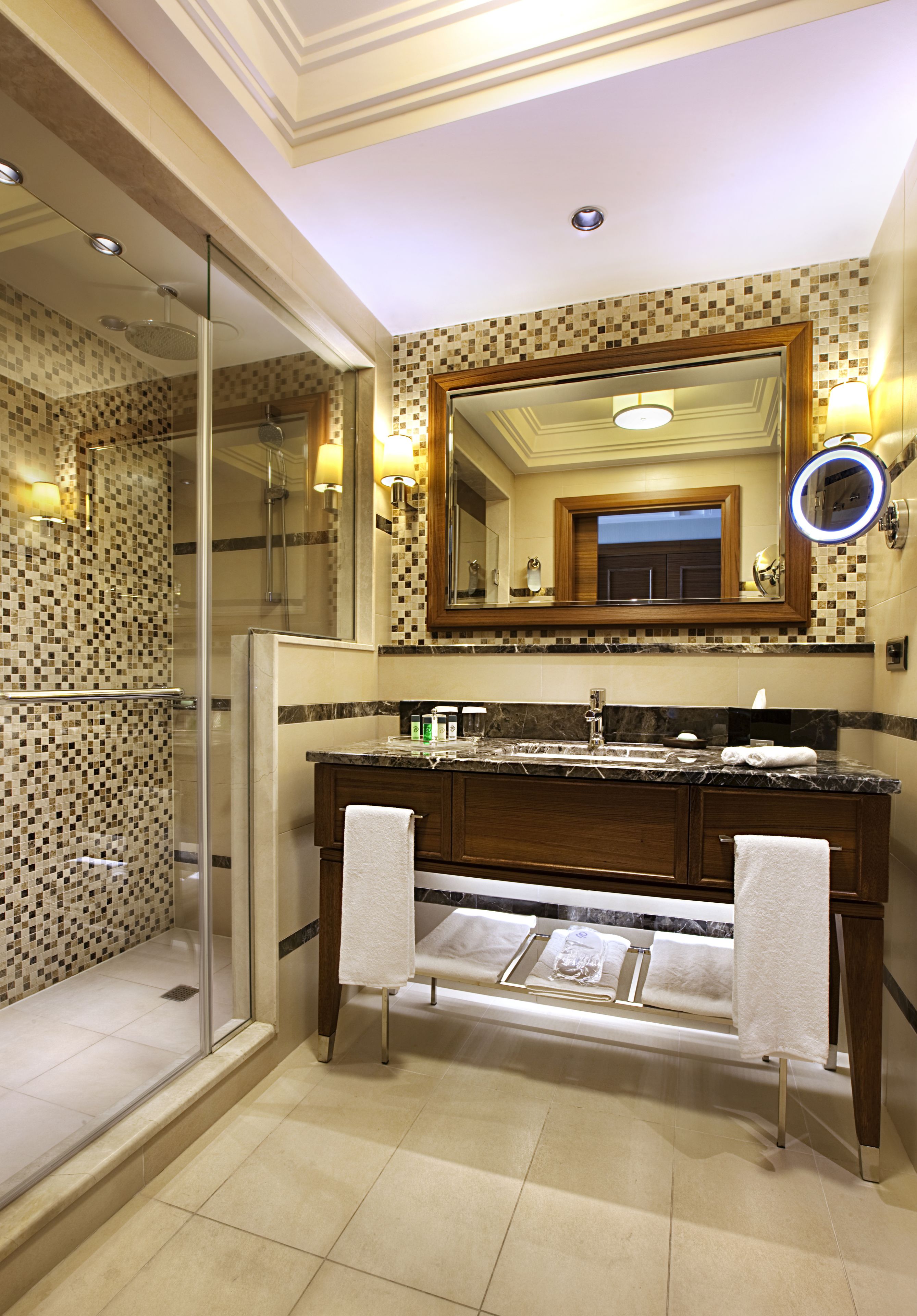 A modern bathroom with a glass shower enclosure, a double vanity with a large mirror, and a tiled floor.